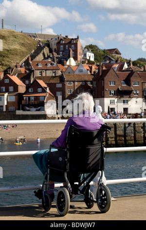 La haute dame en fauteuil roulant donnant sur le port de Whitby Banque D'Images