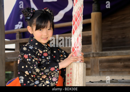 Jeune fille portant un kimono de sonner une cloche à un sanctuaire Shinto au cours de la Cherry Blossom Festival of the Rockies, Japon, Asie Banque D'Images