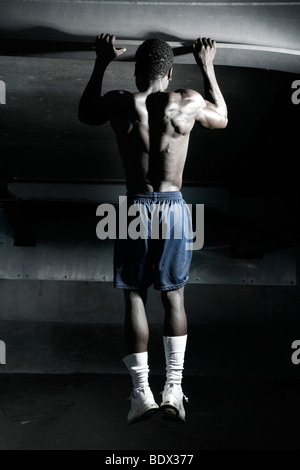 Jeune athlète à la peau sombre, faisant tirer-se lève Banque D'Images