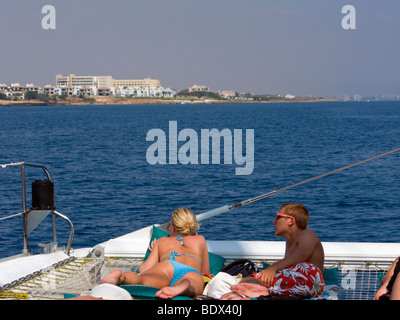 Les touristes sur un catamaran à la recherche sur la plage. Dans l'extrême droite de la photo vous pouvez voir la ville fantôme de Famagouste. Chypre. Banque D'Images