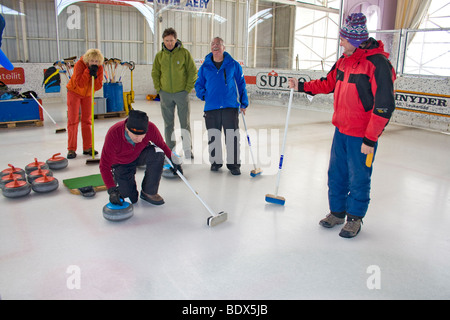 Les visiteurs de Swiss village essayez de curling à la patinoire locale. Banque D'Images