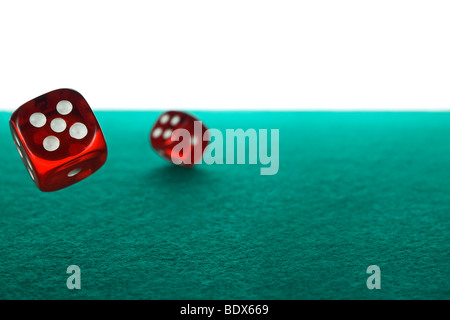 Deux red dices roulant sur un feutre vert sur un fond blanc. Banque D'Images