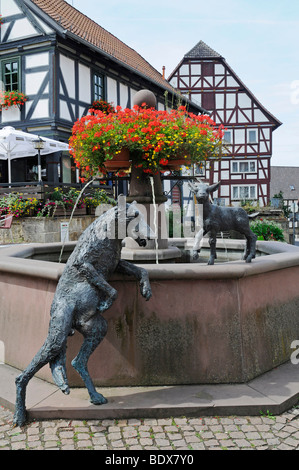 Fontaine avec des sculptures d'un loup et un agneau sur la place du marché de maisons à colombages, Jesberg, National Habichtswald Banque D'Images