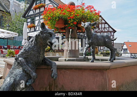 Fontaine avec des sculptures d'un loup et un agneau sur la place du marché de maisons à colombages, Jesberg, National Habichtswald Banque D'Images