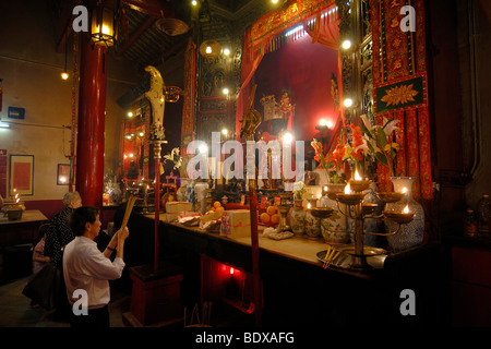L'homme et de la femme en prière avec d'encens, la fumée du sacrifice, en face d'un autel bouddhiste chinois avec des bougies allumées et offrir Banque D'Images