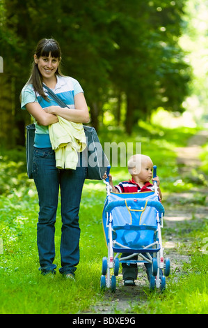 Femme et son fils en parc d'été. Garçon pousser un landau. Banque D'Images