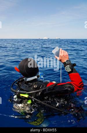 Plongeur à la dérive en mer tente d'obtenir l'attention des gens sur les bateaux de plongée sur l'horizon par un clignotement à l'aide d'un miroir, l'Égypte, R Banque D'Images