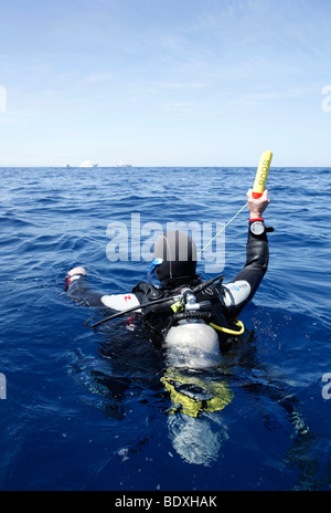 Plongeur à la dérive en mer la tenue d'un émetteur ENOS, une alarme d'urgence électronique et système de repérage, au-dessus du niveau de l'eau, so Banque D'Images