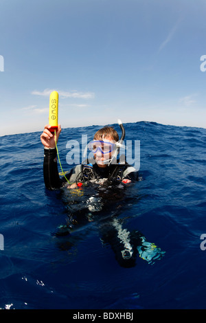 Plongeur à la dérive en mer la tenue d'un émetteur ENOS, une alarme d'urgence électronique et système de repérage, au-dessus du niveau de l'eau, so Banque D'Images