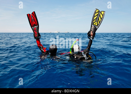 Les plongeurs à la dérive en mer s'efforcent d'obtenir l'attention des gens sur les bateaux de plongée sur l'horizon en l'agitant avec leurs palmes de plongée, Banque D'Images