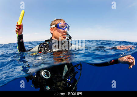 Plongeur à la dérive en mer la tenue d'un émetteur ENOS, une alarme d'urgence électronique et système de repérage, au-dessus du niveau de l'eau, so Banque D'Images