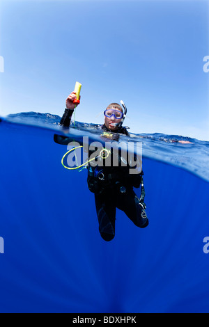 Plongeur à la dérive en mer la tenue d'un émetteur ENOS, une alarme d'urgence électronique et système de repérage, au-dessus du niveau de l'eau, so Banque D'Images