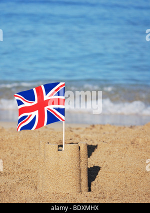 Union Jack drapeau sur le toit d'un château de sable sur la plage Banque D'Images