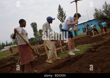 Un écolier anglais public aide les sections locales dans un village rwandais creuser une fondation pour une nouvelle salle. Banque D'Images