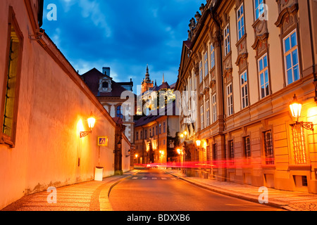 Le château de Prague illumine le ciel nocturne, projetant une lueur chaude sur les rues historiques Banque D'Images