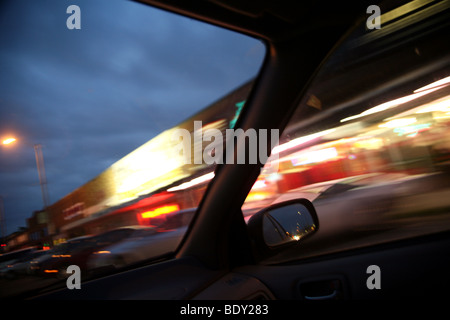 Voiture à la nuit en descendant la route. Les lumières de la ville floues à l'extérieur de la fenêtre. Banque D'Images