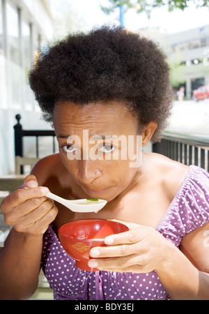 African American Woman eating Soupe miso au café en plein air, Vancouver Banque D'Images