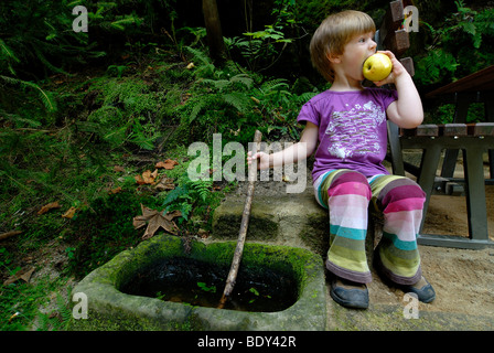 Petite fille de mordre en tenant un petit morceau d'une pomme, l'occasion d'une randonnée dans le Parc National de la Suisse Saxonne, Kirnitschtal valley, OBE Banque D'Images