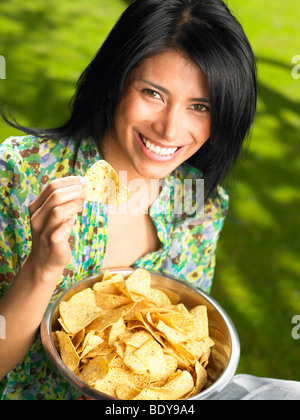 Woman eating chips, outdoors Banque D'Images