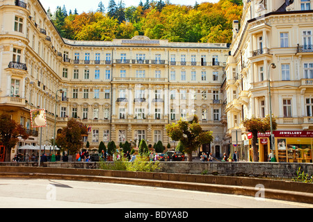 Élégant Grandhotel Pupp à Karlovy Vary avec une façade historique ornée, des arbres d'automne, des boutiques et des gens marchant devant la place de la ville thermale Banque D'Images