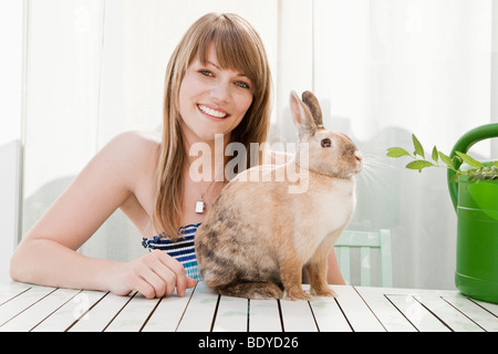 Jeune femme et d'un animal de compagnie lapin sur un patio Banque D'Images