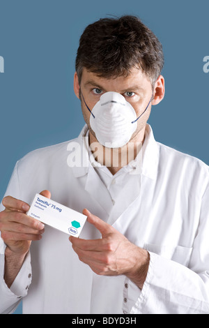 Médecin avec masque de protection présentant le médicament Tamiflu Banque D'Images