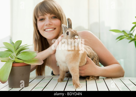 Jeune femme et d'un animal de compagnie lapin sur un patio Banque D'Images