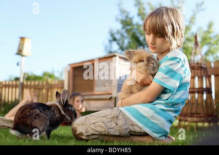 Garçon jouant avec lapin dans jardin Banque D'Images