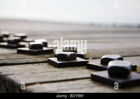 Une ligne d'écrous et boulons tenant ensemble une jetée en bois. Banque D'Images