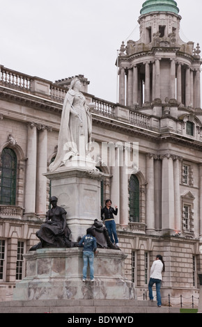 Belfast City Hall avec statue de la reine Victoria et les touristes posant sur la plinthe Banque D'Images