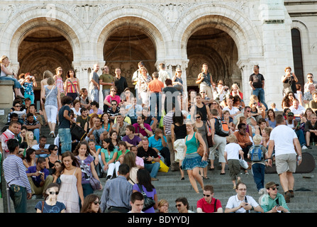 People enjoying the entertainment on the steps of the Sacre Coeur, Montmartre, Paris France Banque D'Images