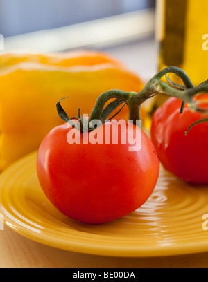 Succulentes tomates rouges frais avec vigne sur plaque jaune Banque D'Images