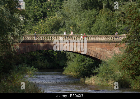 Personnes marchant sous le soleil d'été à travers le pont victorien Prince of Wales, Kelvingrove Park, Glasgow West End, Écosse, Royaume-Uni Banque D'Images