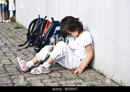 Jeune fille assise dans la cour de l'école, triste Banque D'Images