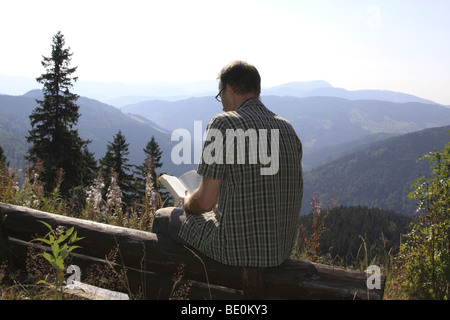 L'homme, mi 40s, assis sur un banc, lisant un livre, la montagne Silberberg, Forêt-Noire, Bade-Wurtemberg, Allemagne, Europe Banque D'Images