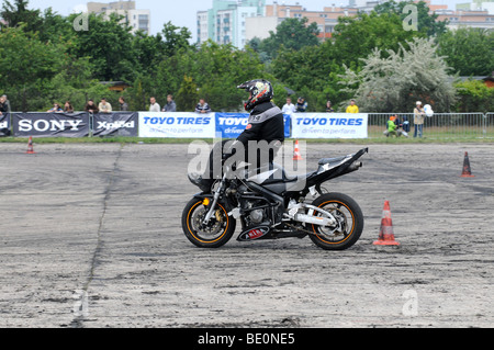 Stunt riders Streetbike freestyle show à Varsovie, Pologne. Homme monté sur sa moto tout en étant assis sur le réservoir de combustible et les barres de poignée Banque D'Images