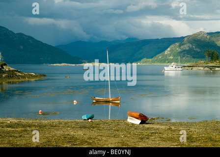 Bateaux reposant sur les rives de Plockton dans le nord-ouest des Highlands d'Écosse, avec des eaux calmes et une tempête brewing Banque D'Images