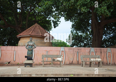 En dehors du Temple de pythons dans Oudiah, Bénin, une chèvre se trouve au pied d'une statue d'une femme avec un python. Banque D'Images