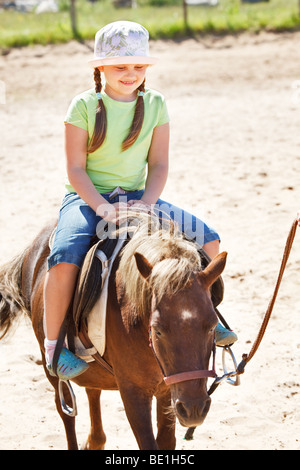 Little girl smiling and riding pony Banque D'Images