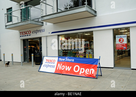 Tesco Express avec nouveau magasin maintenant ouvert affiche à l'extérieur et petit chien en attente de son propriétaire Banque D'Images