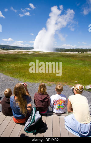 Une famille regarder Old Faithful Geyser à Parc National de Yellowstone, Wyoming Banque D'Images