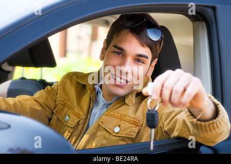 Jeune homme assis à l'intérieur montrant les clés de voiture nouvelle voiture Banque D'Images