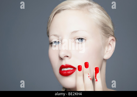 Portrait d'une jeune femme blonde avec des taches de vernis à ongles à la recherche vers l'observateur, l'imparfait, la beauté Banque D'Images