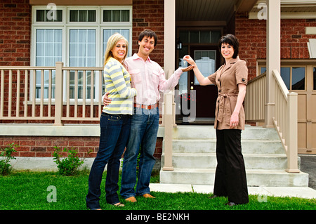 Couple heureux obtenir les clés de maison neuve d'agent immobilier Banque D'Images