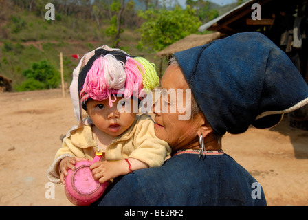 La pauvreté, portrait, l'ethnologie, Yao femme vêtue d'un costume traditionnel avec un bébé dans les bras, village de Ban Gno, Houeyyoum Banque D'Images