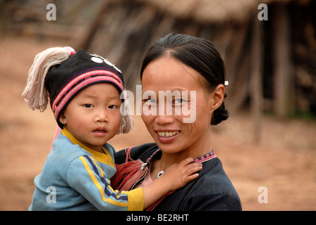 La pauvreté, portrait, l'ethnologie, Yao femme vêtue d'un costume traditionnel, souriant avec un bébé dans les bras, village de Ban Houey Banque D'Images