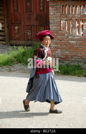 Le bouddhisme tibétain, l'ethnologie, femme de l'ethnie Mosu habillé en costume traditionnel balancer un moulin à prières, Luoshui, Lugu Banque D'Images