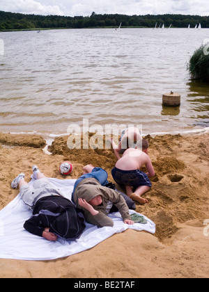 Les garçons jouent sur la plage par l'eau à Frensham Great Pond. Churt, près de Farnham, Surrey. UK. Banque D'Images