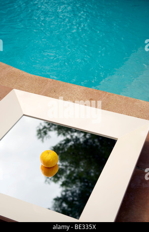 Un seul la mandarine se trouve dans milieu de télévision miroir encadré blanc à côté d'une piscine Banque D'Images