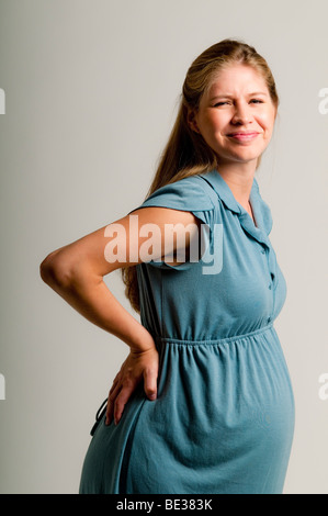 Pregnant woman holding back Banque D'Images